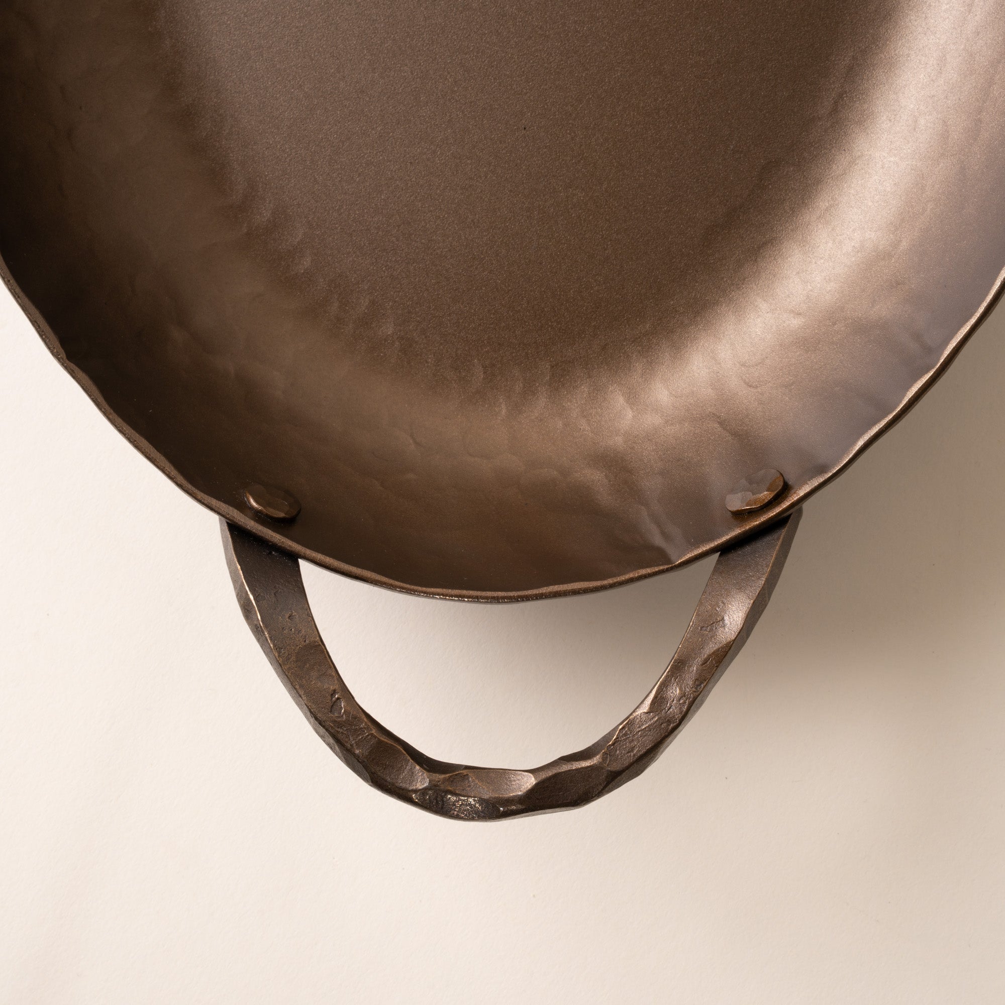 A closeup of the handle of a hammered metal oval roasting pan