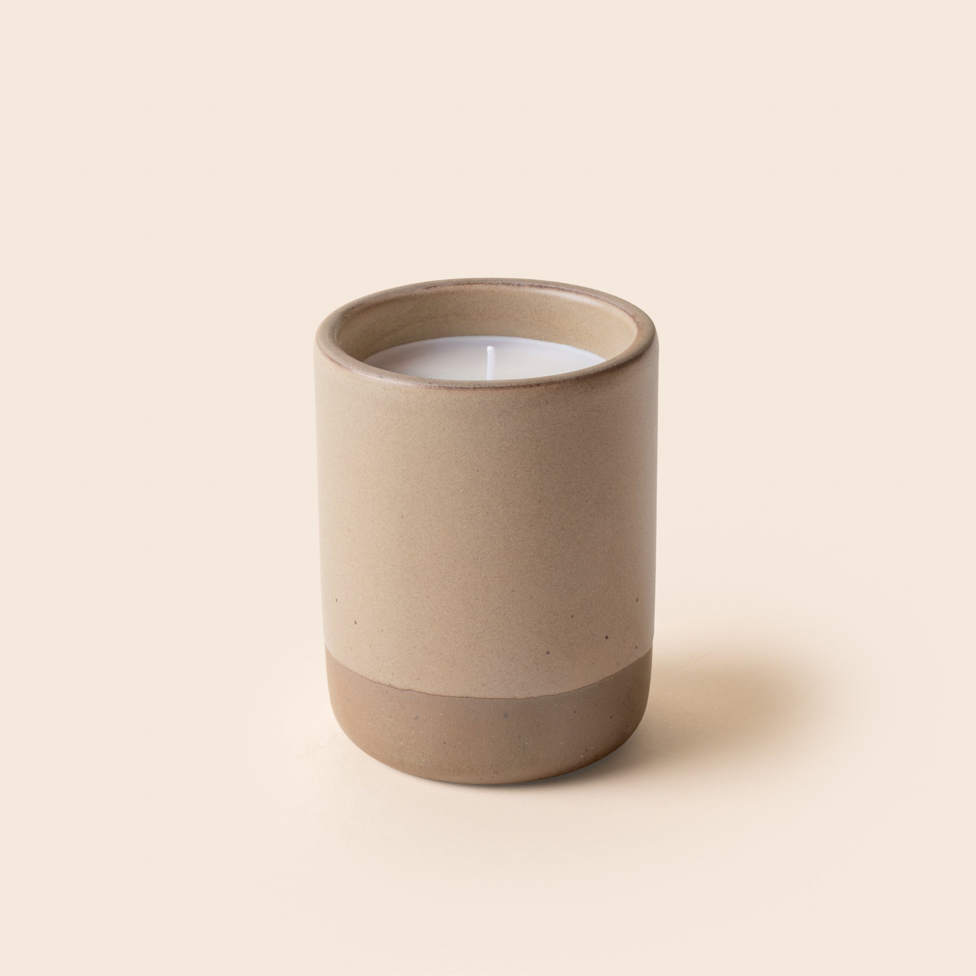 Large ceramic vessel in a warm pale brown color with candle inside.