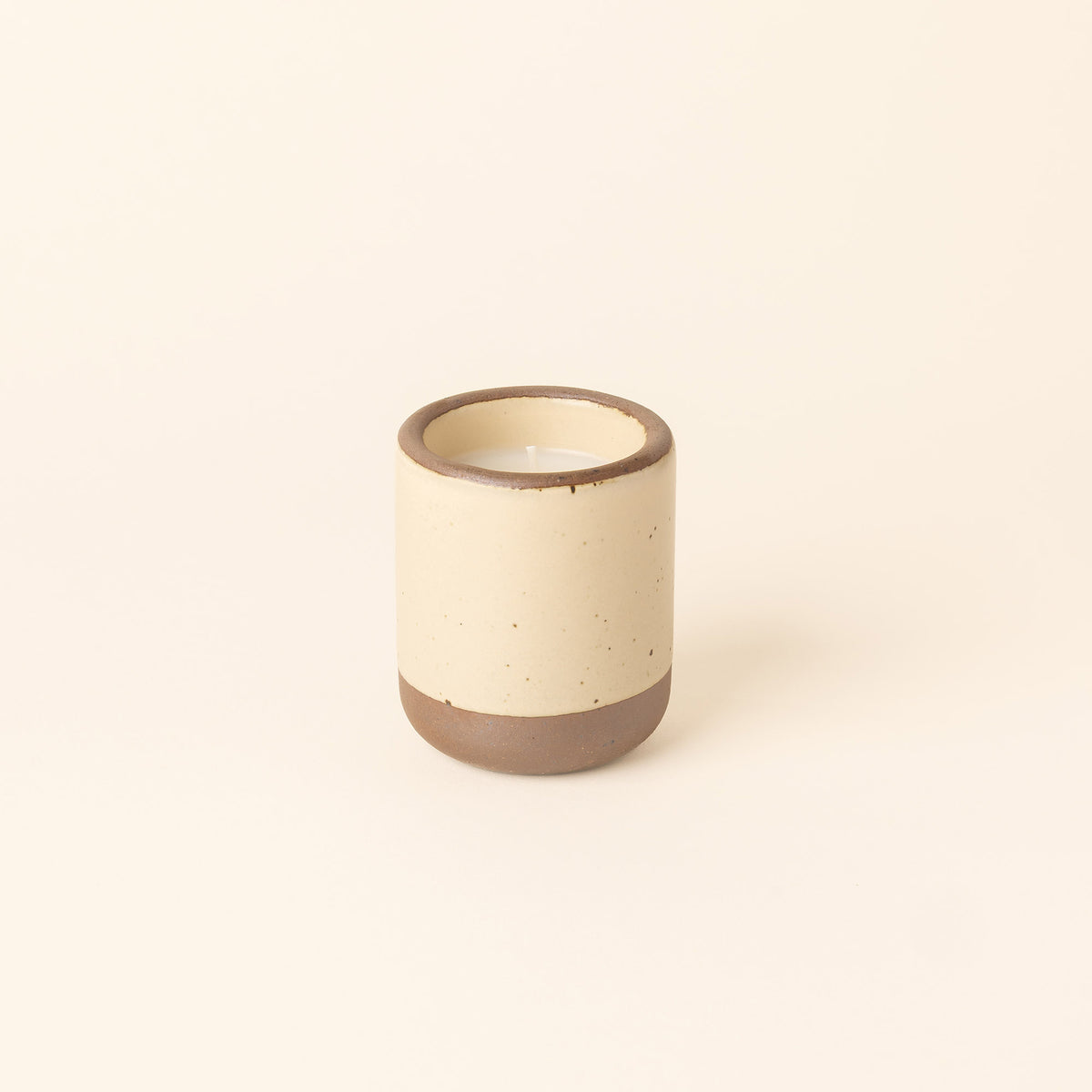 Small ceramic vessel in a cream color with candle inside.