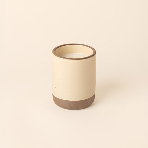 Large ceramic vessel in a cream color with candle inside.