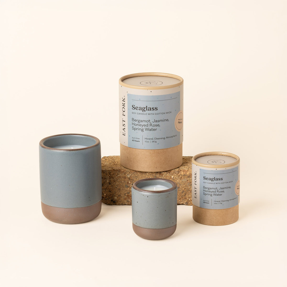 Small and large ceramic vessels in an blue-grey color with candle inside each with packaging.
