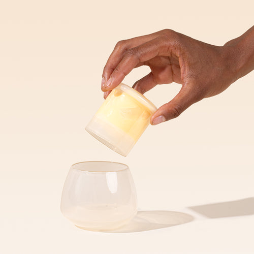 A hand holds the top of the cream clear butter keeper over the rounded base.