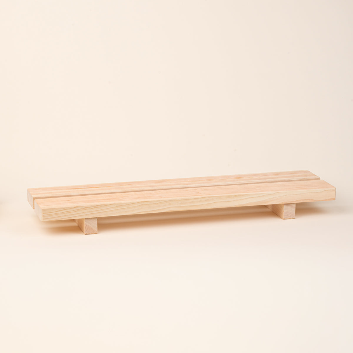 A long, low unfinished-wood bath tray made from two parallel planks, with simple block feet. 