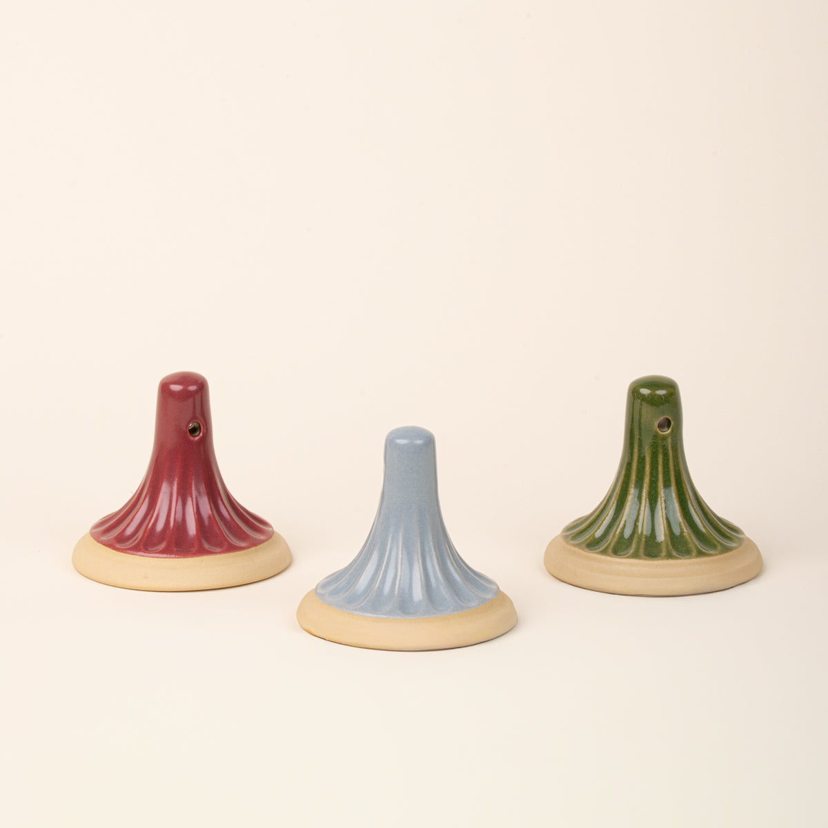 Three ceramic stamps with a cream colored base in a light blue, green, and red colors.