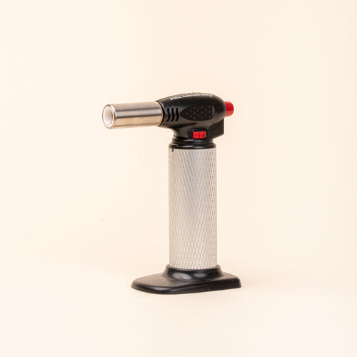Black and silver culinary torch with red controls on a light background.
