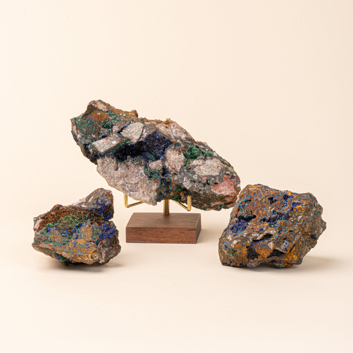 Azurite displayed on a wood display stand with brass prongs, with 2 more pieces of azurite.