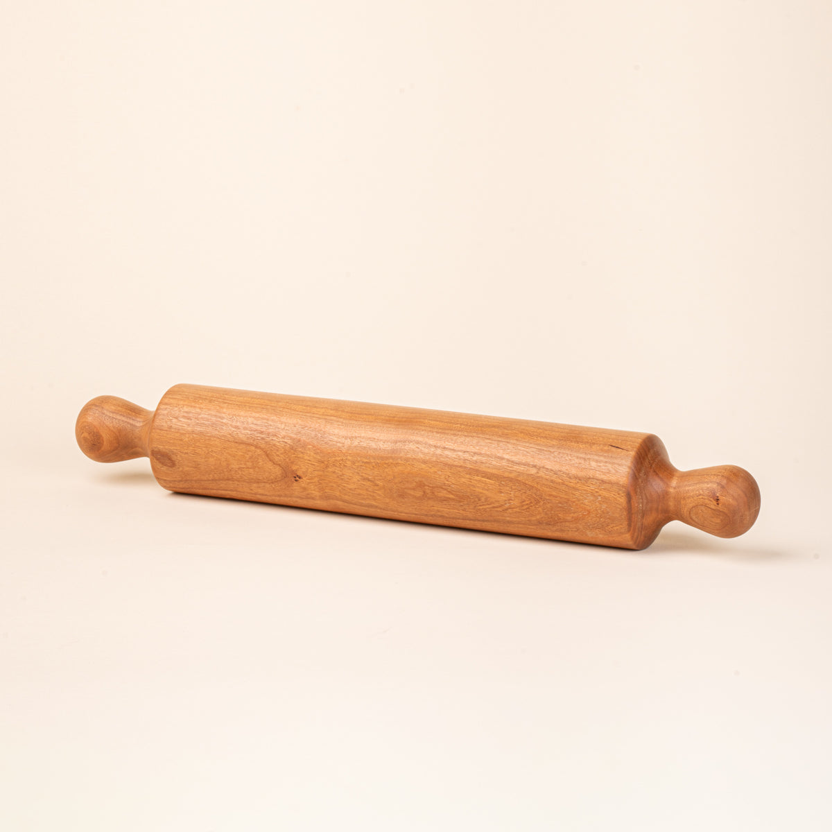 A simple dowel wooden rolling pin with rounded handles, in cherry.
