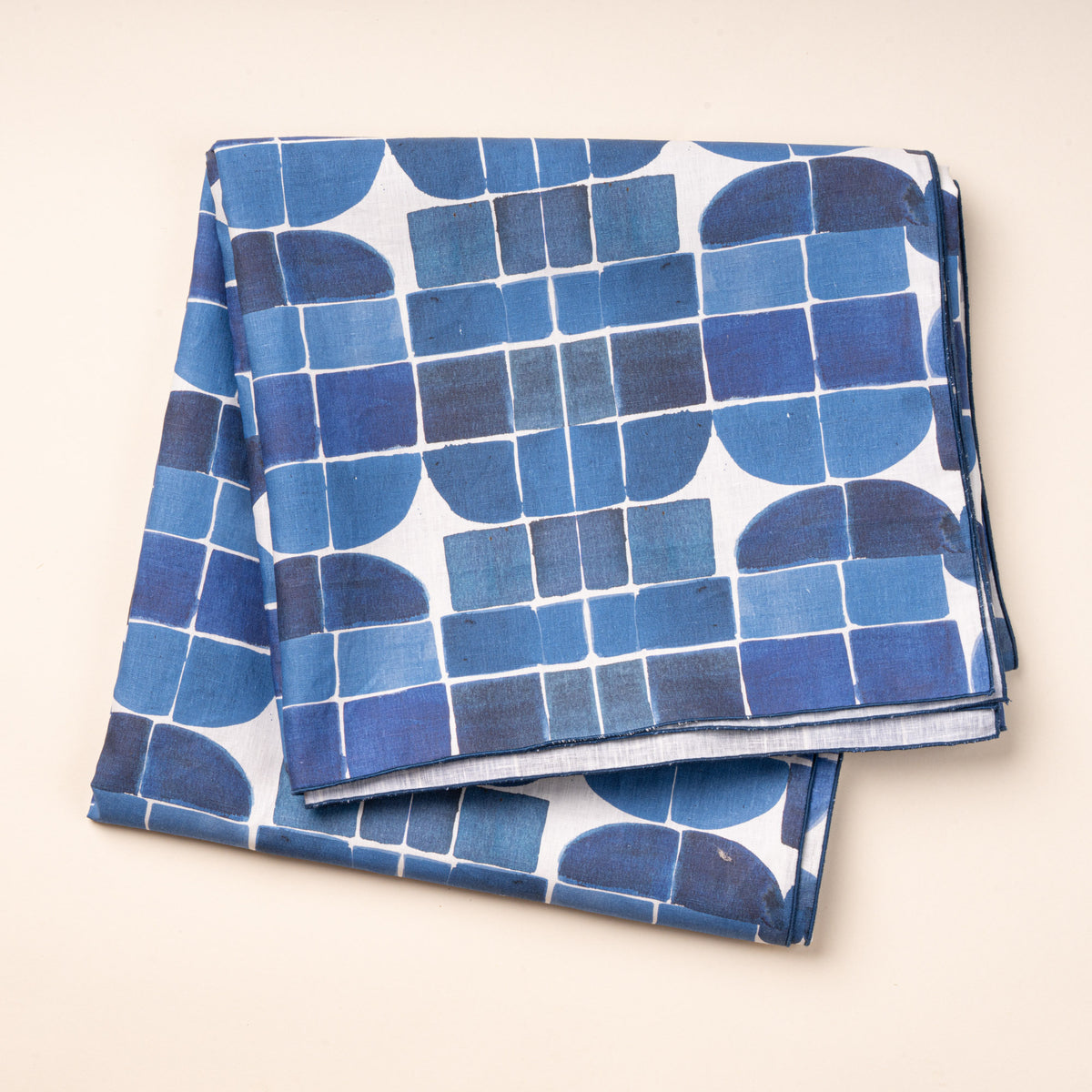 A blue-and-white cloth tablecloth featuring a bold geometric pattern of squares, curves, and intersecting lines.