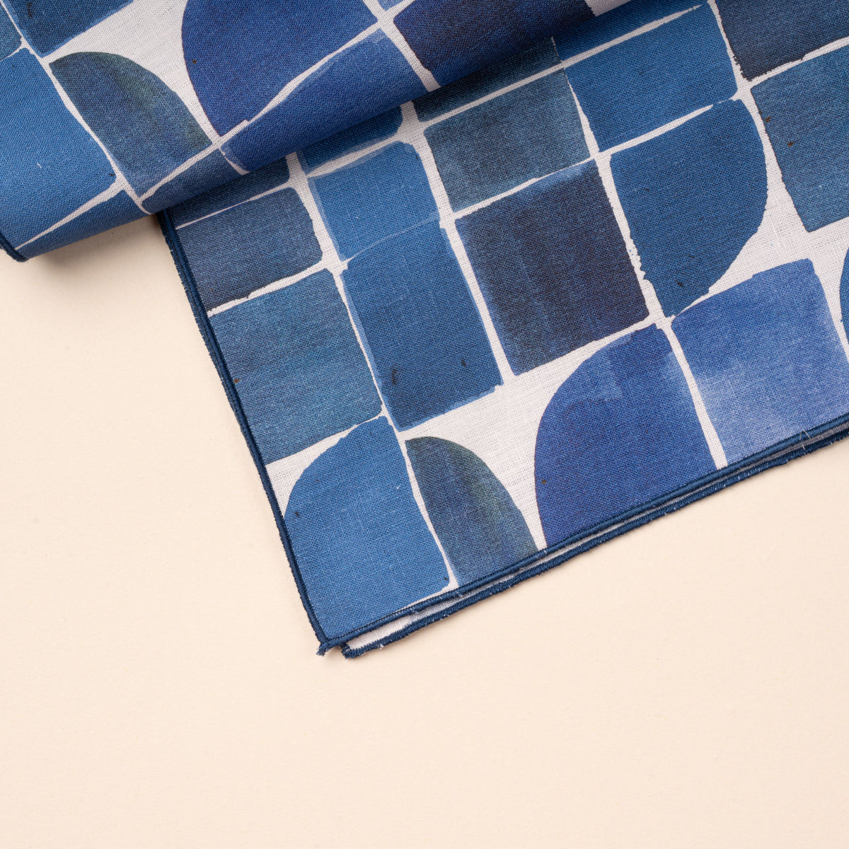 A closeup of a blue-and-white cloth table runner featuring a bold geometric pattern of squares, curves, and intersecting lines.
