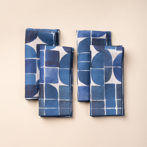 Set of four blue-and-white cloth napkins featuring a bold geometric pattern of squares, curves, and intersecting lines.