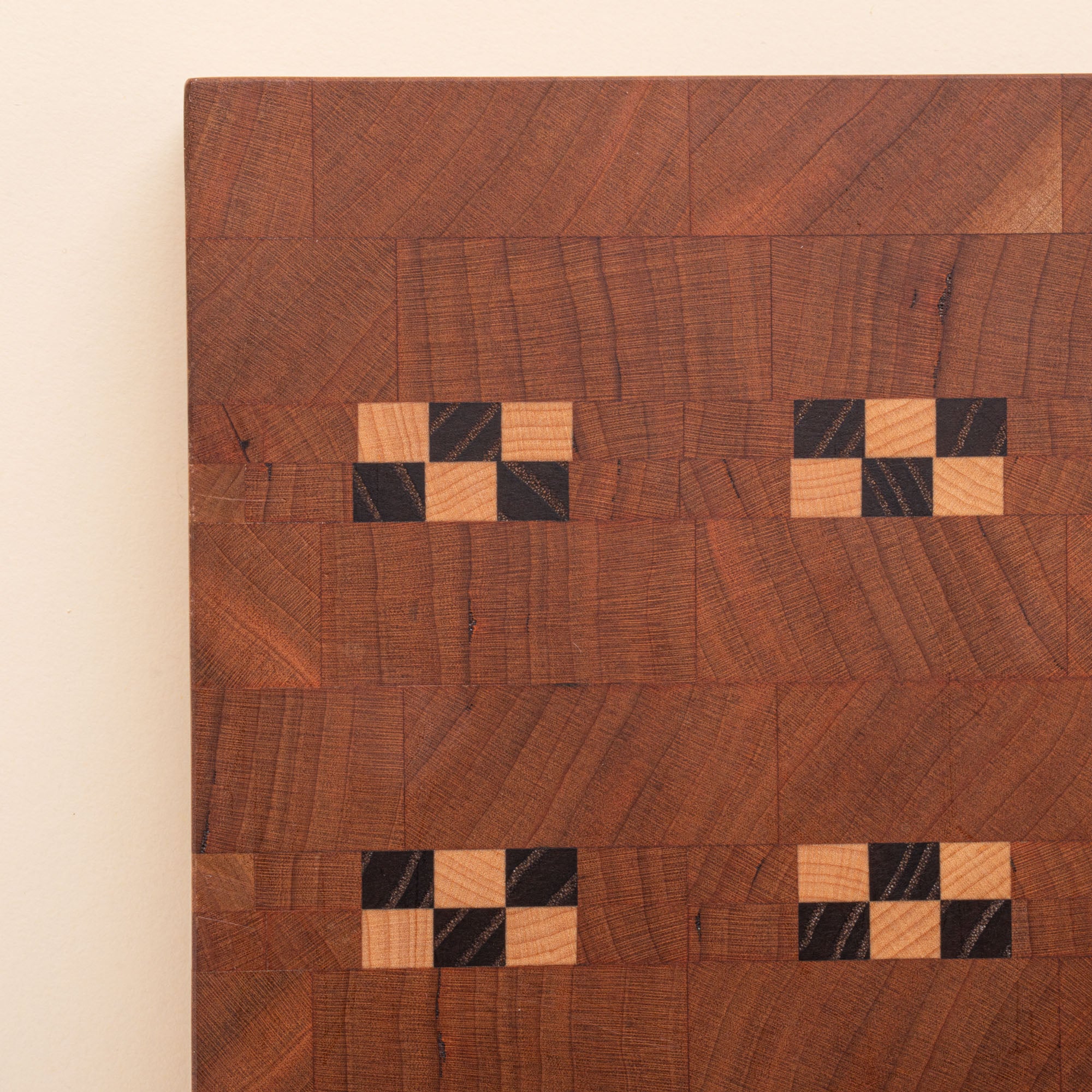 Closeup of a rectangular wooden cutting board with repeating geometric inlay pattern