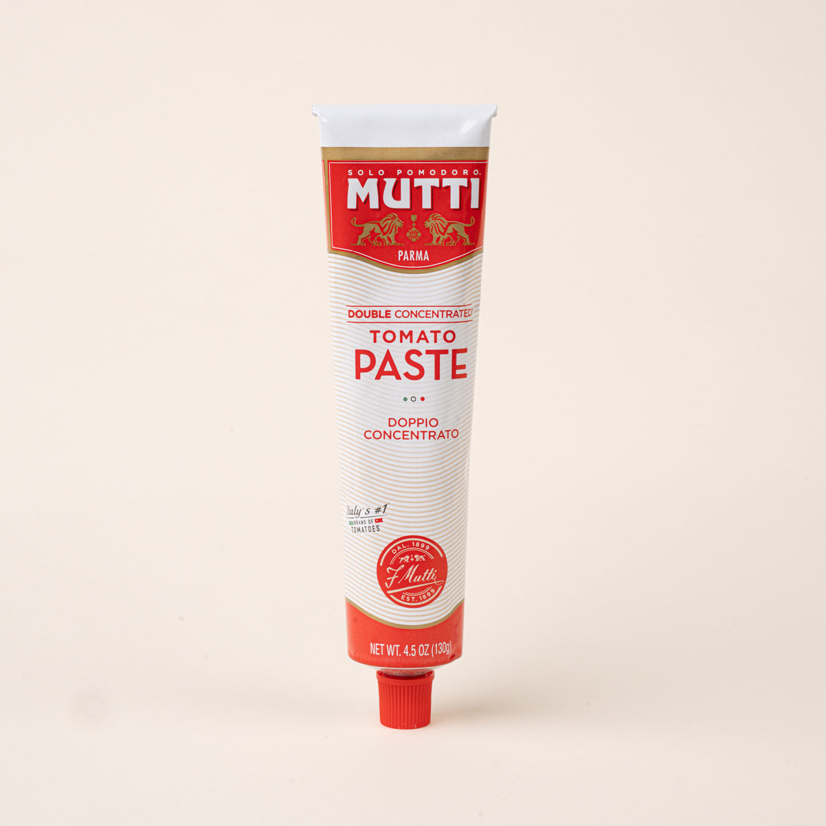 Tube of Mutti double concentrated tomato paste with red and white packaging and a red screw cap on a cream background.