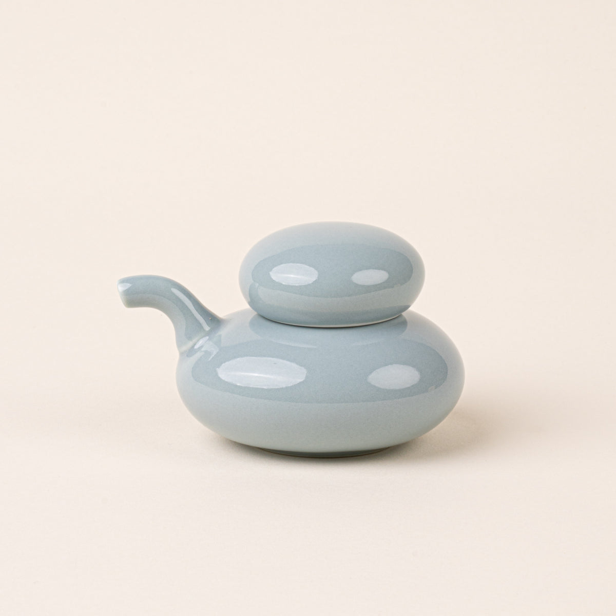 A pale blue glazed ceramic soy sauce pot with a low, rounded body, short pouring spout, and domed lid.