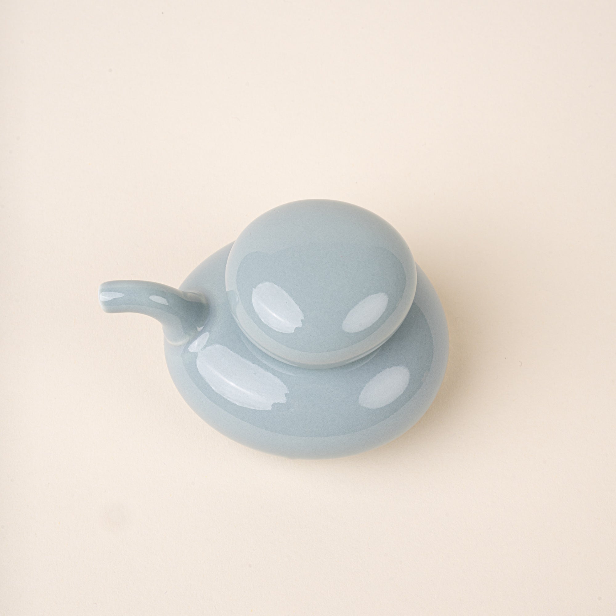 An overhead view of a pale blue glazed ceramic soy sauce pot with a low, rounded body, short pouring spout, and domed lid.