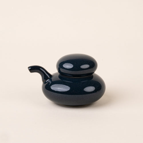A navy glazed ceramic soy sauce pot with a low, rounded body, short pouring spout, and domed lid.