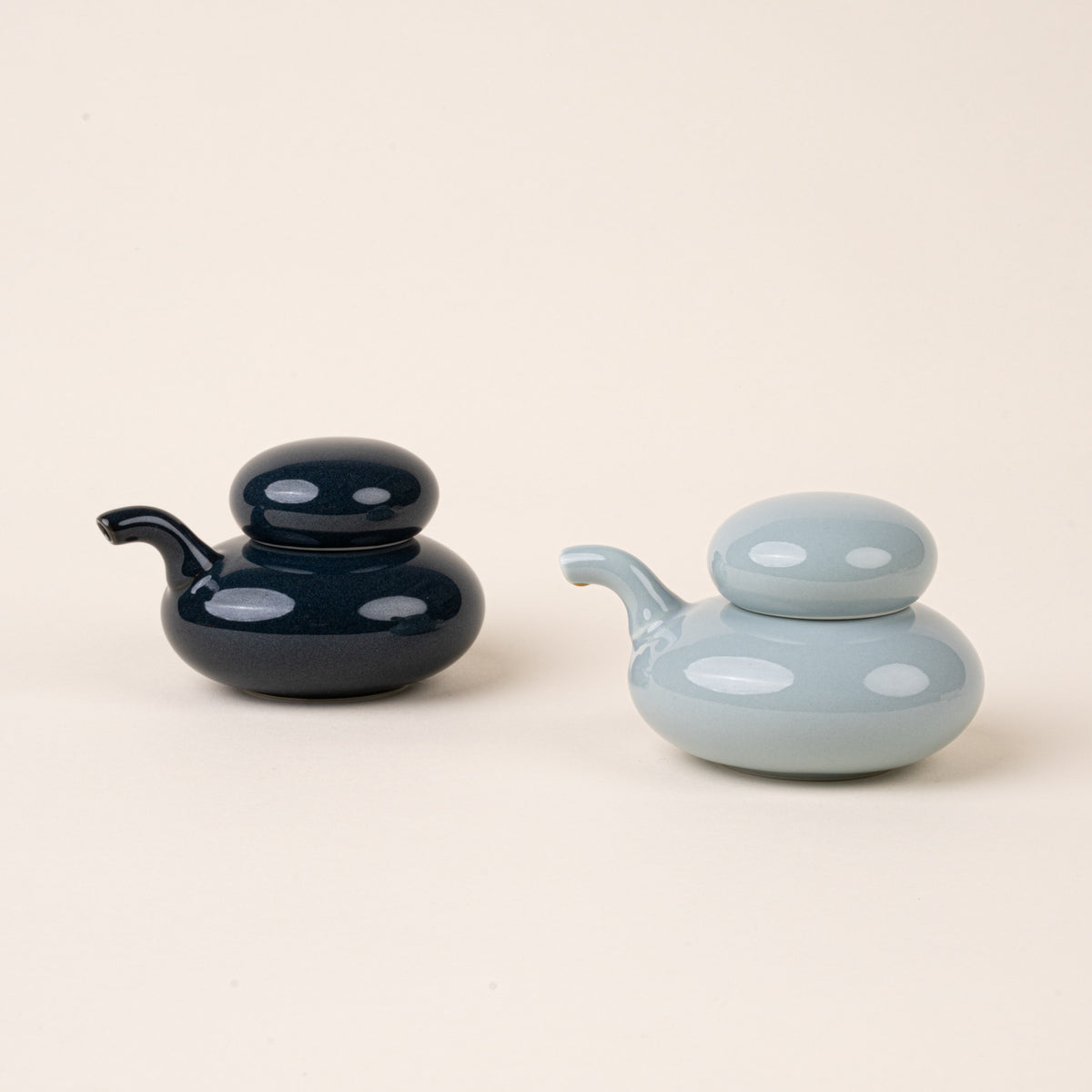 A pale blue and navy glazed ceramic soy sauce pots with a low, rounded body, short pouring spout, and domed lids.