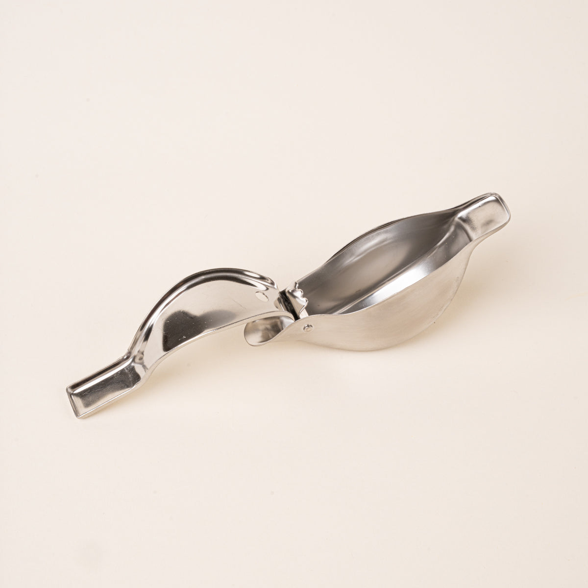An open sculptural stainless-steel lemon squeezer with a bird-like silhouette.