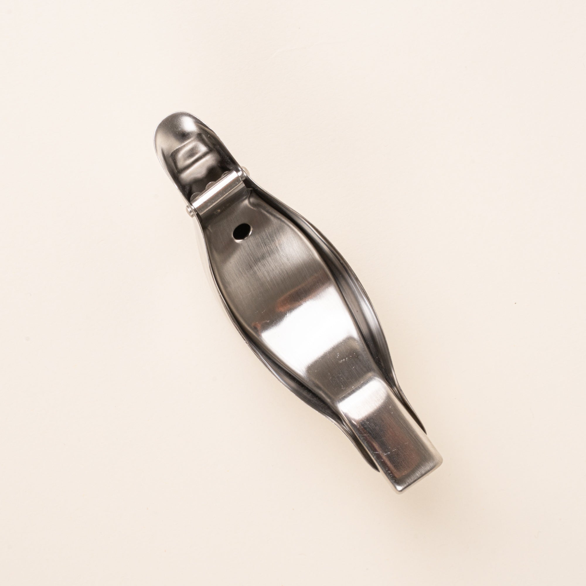 Overhead view of a sculptural stainless-steel lemon squeezer with a bird-like silhouette.