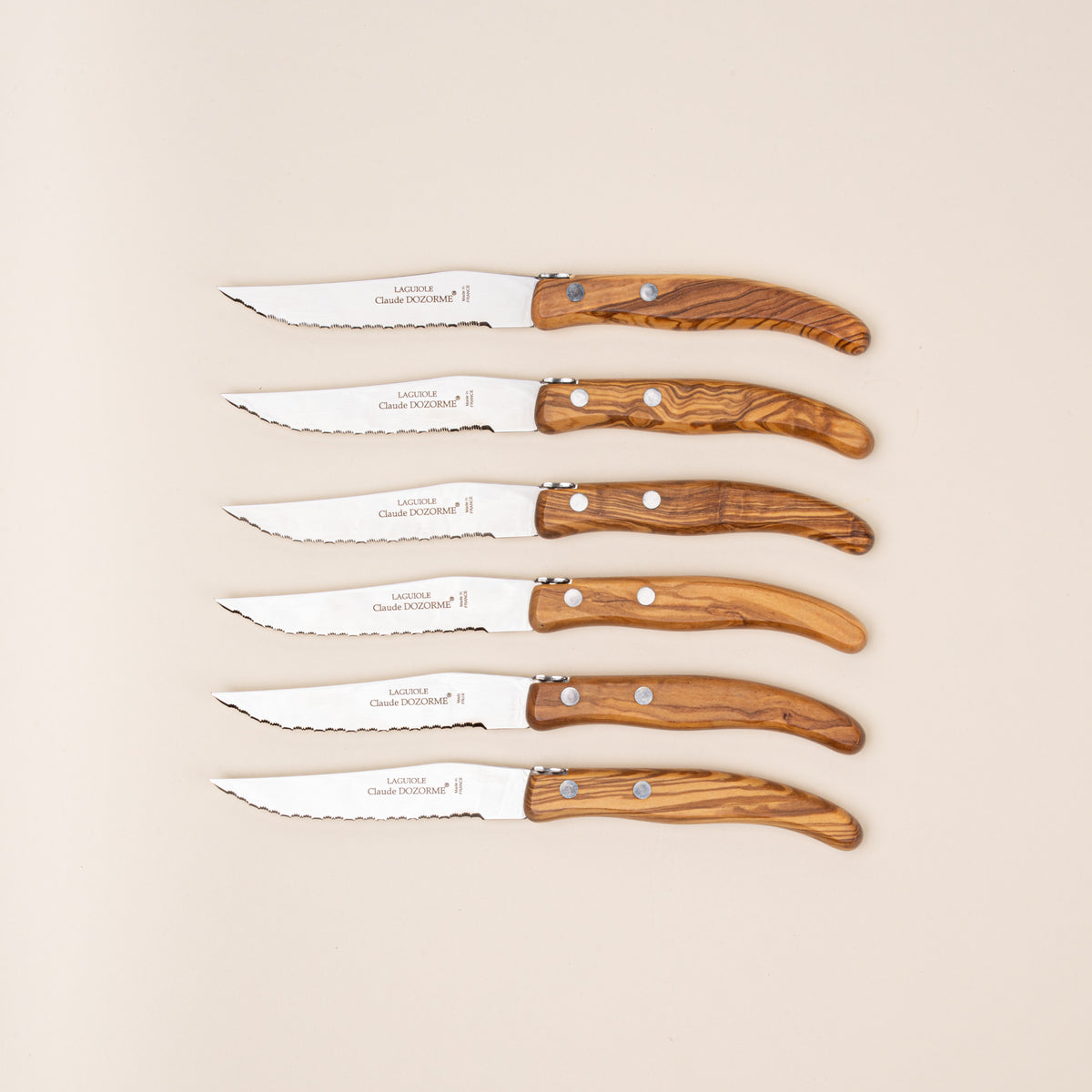 Set of six steak knives with polished steel blades and richly grained olive wood handles.