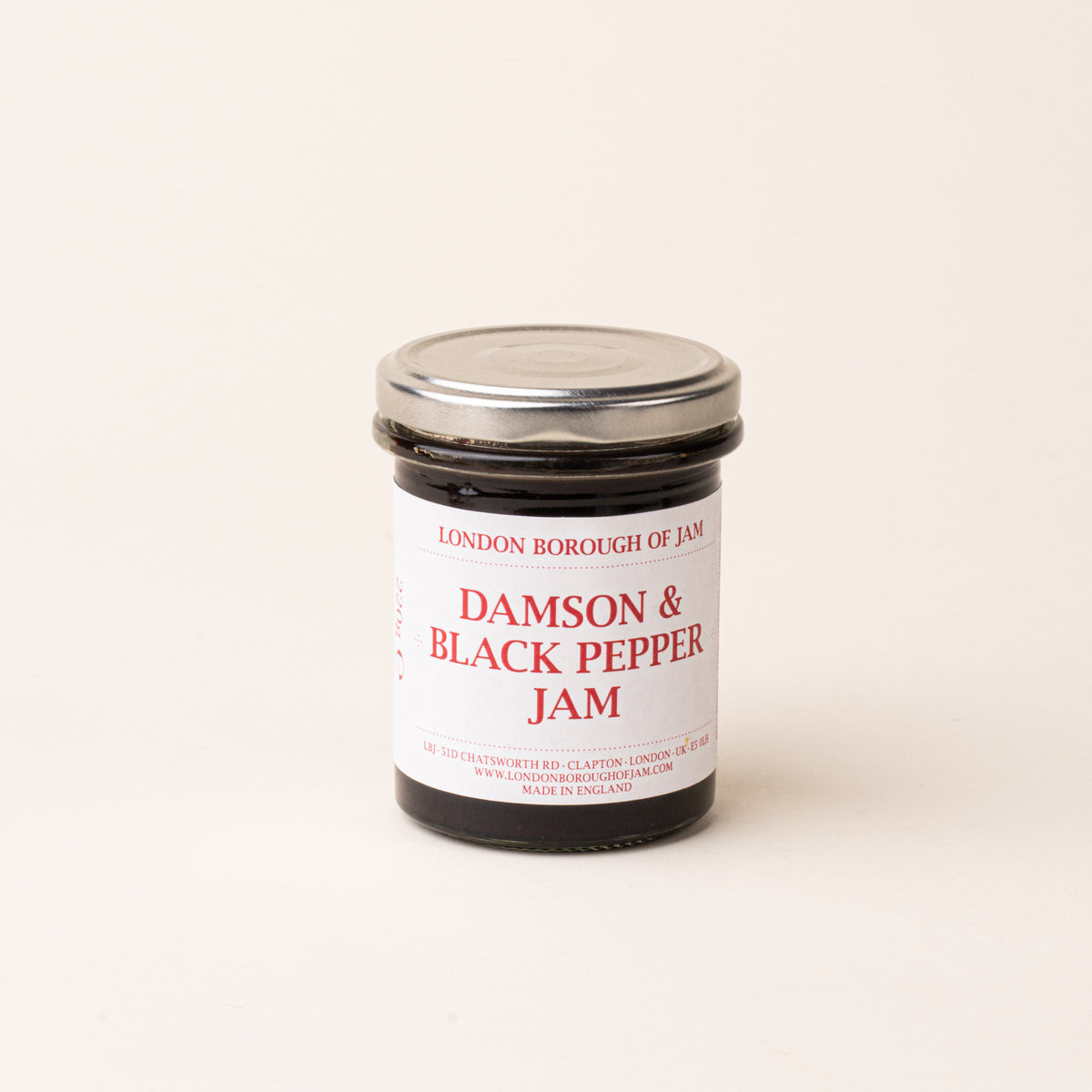 A glass jar with a white label of 'Damson & Black Pepper Jam'