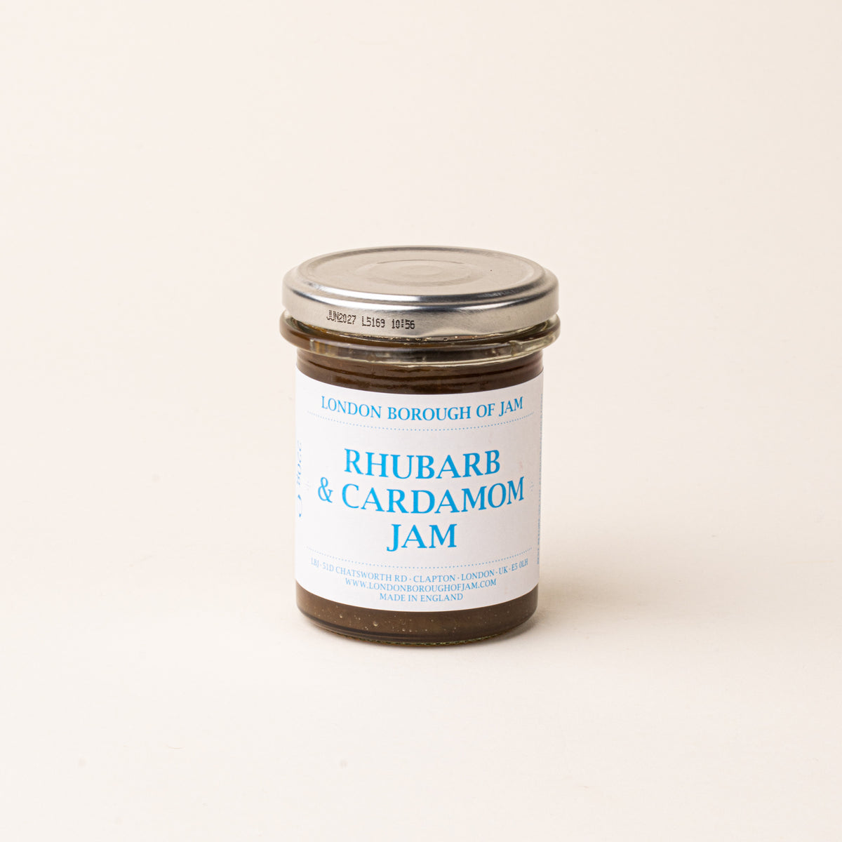 A glass jar with a white label of 'Rhubarb & Cardamom Jam'