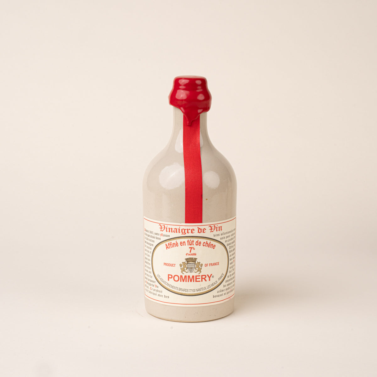 White ceramic bottle of Pommery red wine vinegar with a red wax seal, ribbon, and printed label.