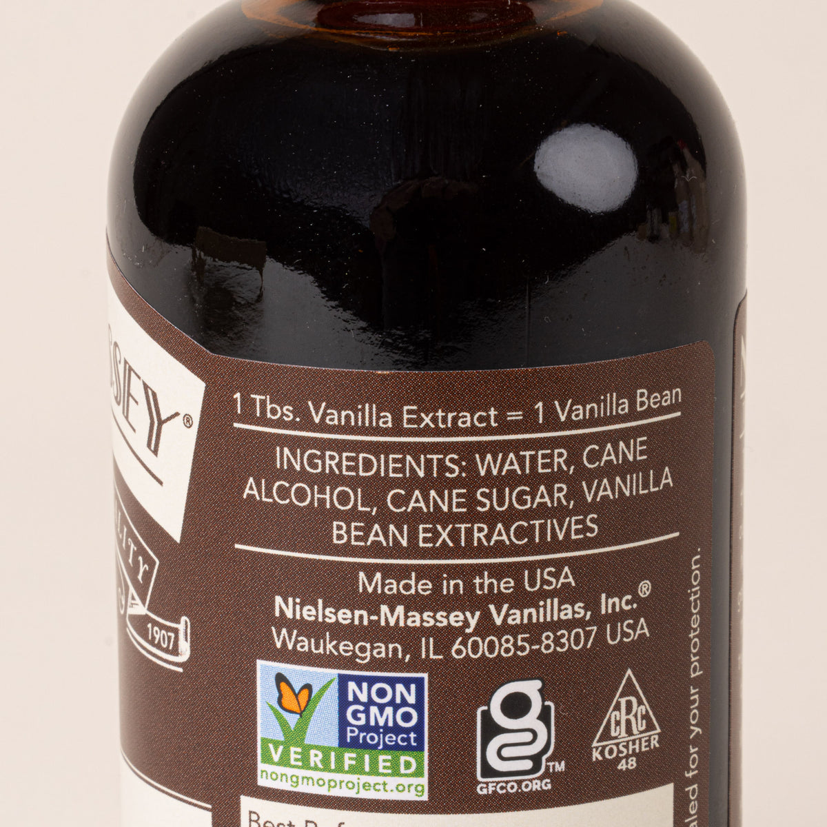 The back of a glass brown jar of Pure Vanilla Extract with a brown and white label, with ingredients listed.