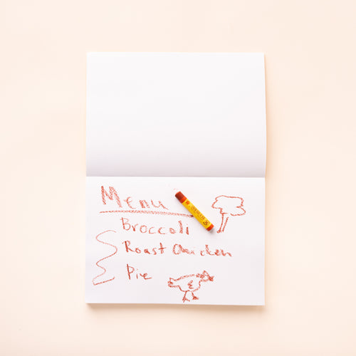An open sketchpad with a drawing of broccoli and chicken and a menu with a red crayon.
