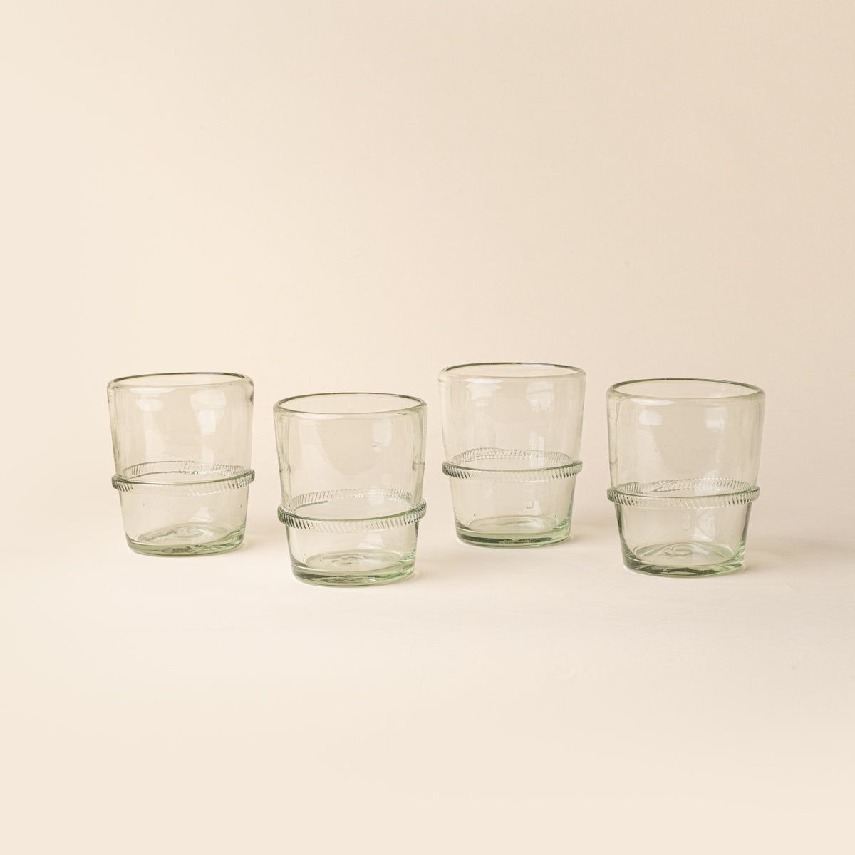 Set of four clear short recycled glass tumblers with a ridged band detail.