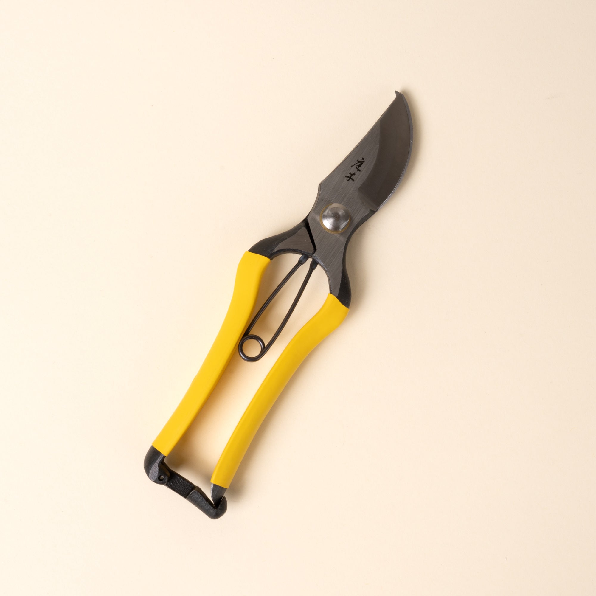 Closed yellow-handled pruning shears with metal blades and spring mechanism, shown on a neutral background.