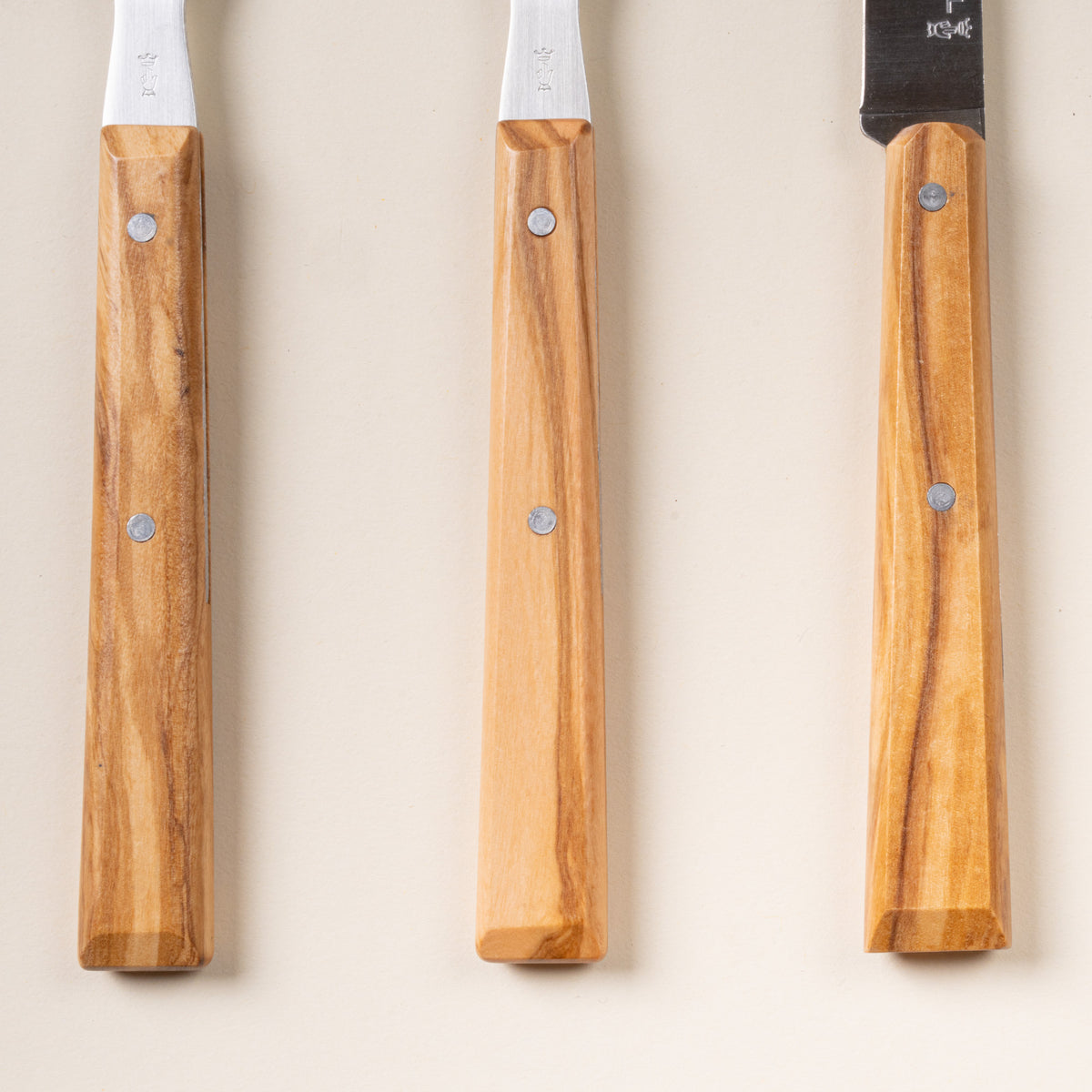Closeup of 3 Opinel table knives and forks with wooden handles.
