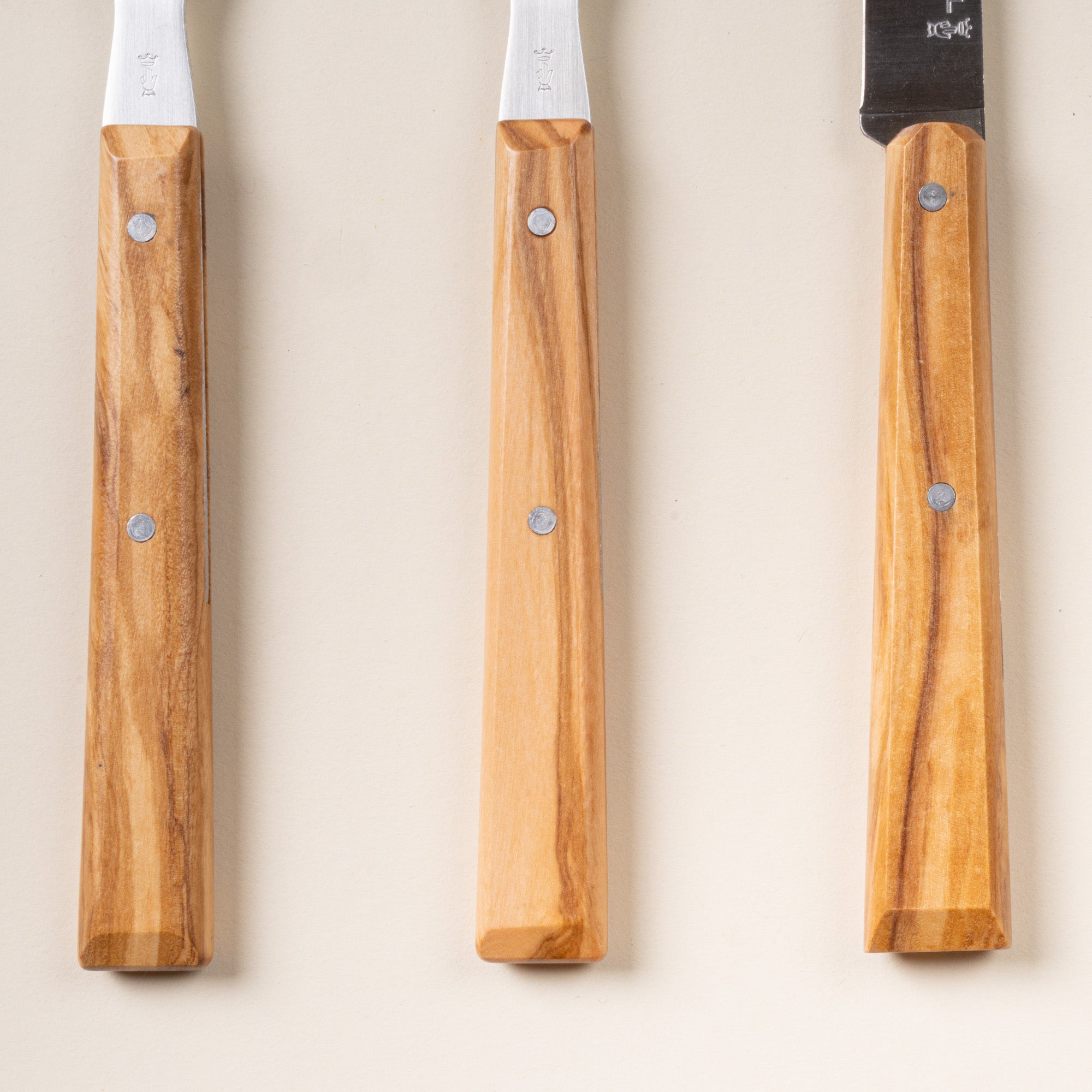 Closeup of 3 Opinel table knives and forks with wooden handles.