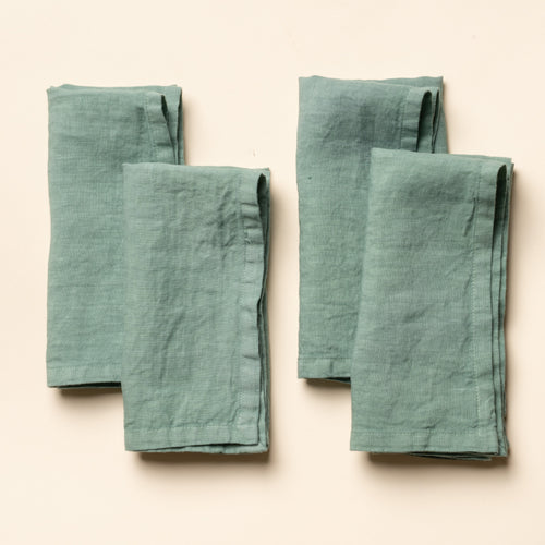 4 folded linen napkins in a green color