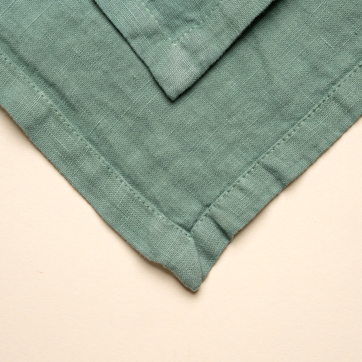 Closeup of a corner of a folded linen napkin in green color