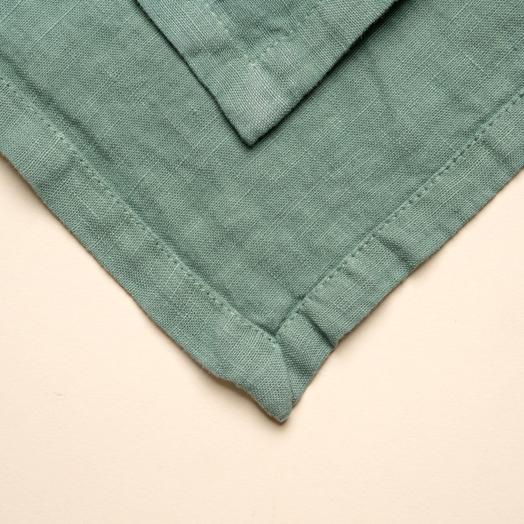 Closeup of a corner of a folded linen napkin in green color