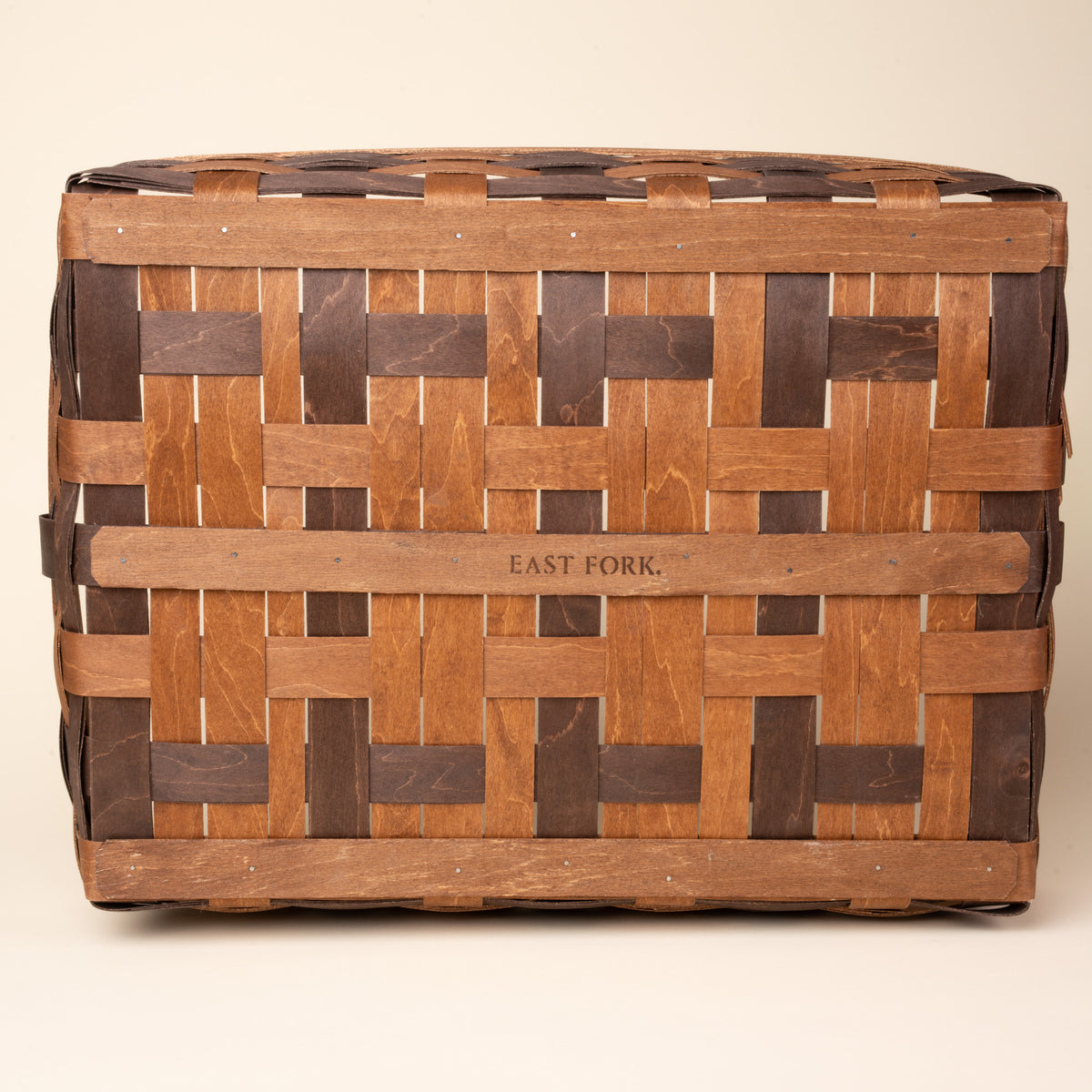 Bottom of the rectangular woven wood basket in two-tone brown with an open top and reinforced rim, with an engraving that reads 'EAST FORK'.