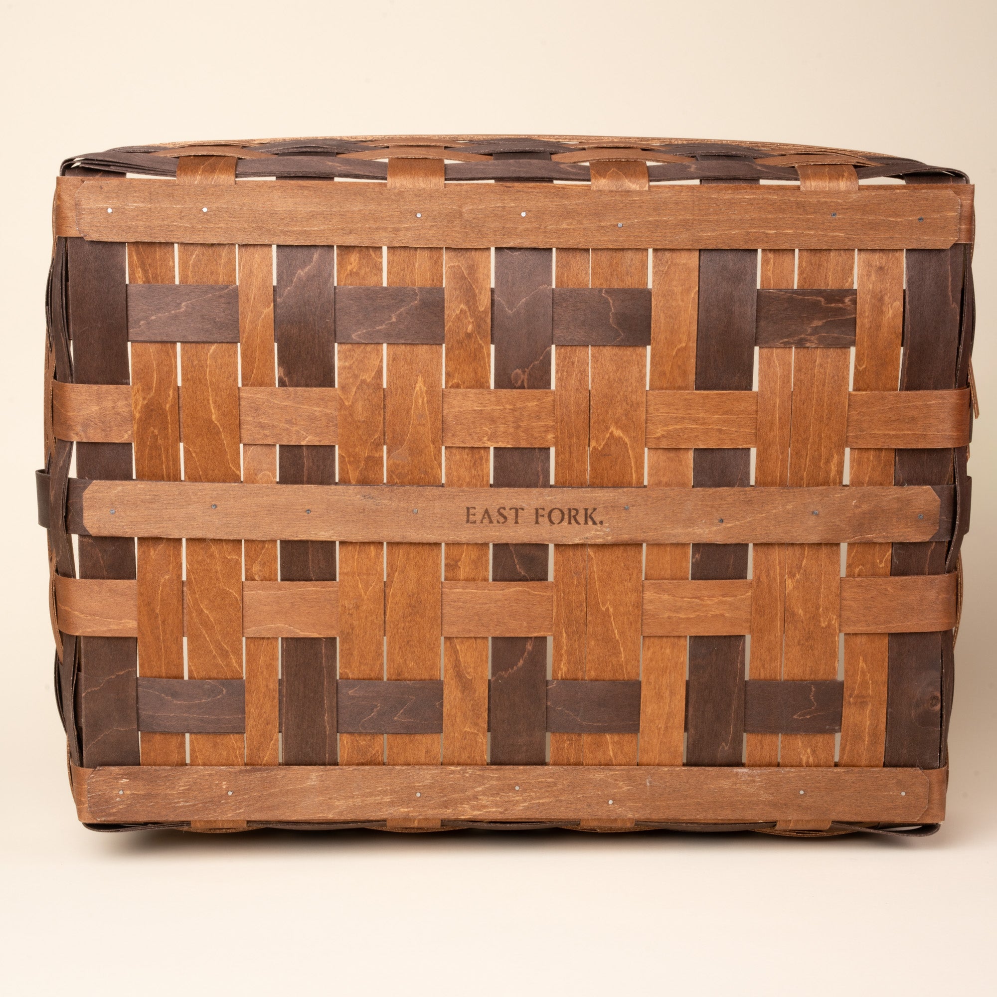 Bottom of the rectangular woven wood basket in two-tone brown with an open top and reinforced rim, with an engraving that reads 'EAST FORK'.