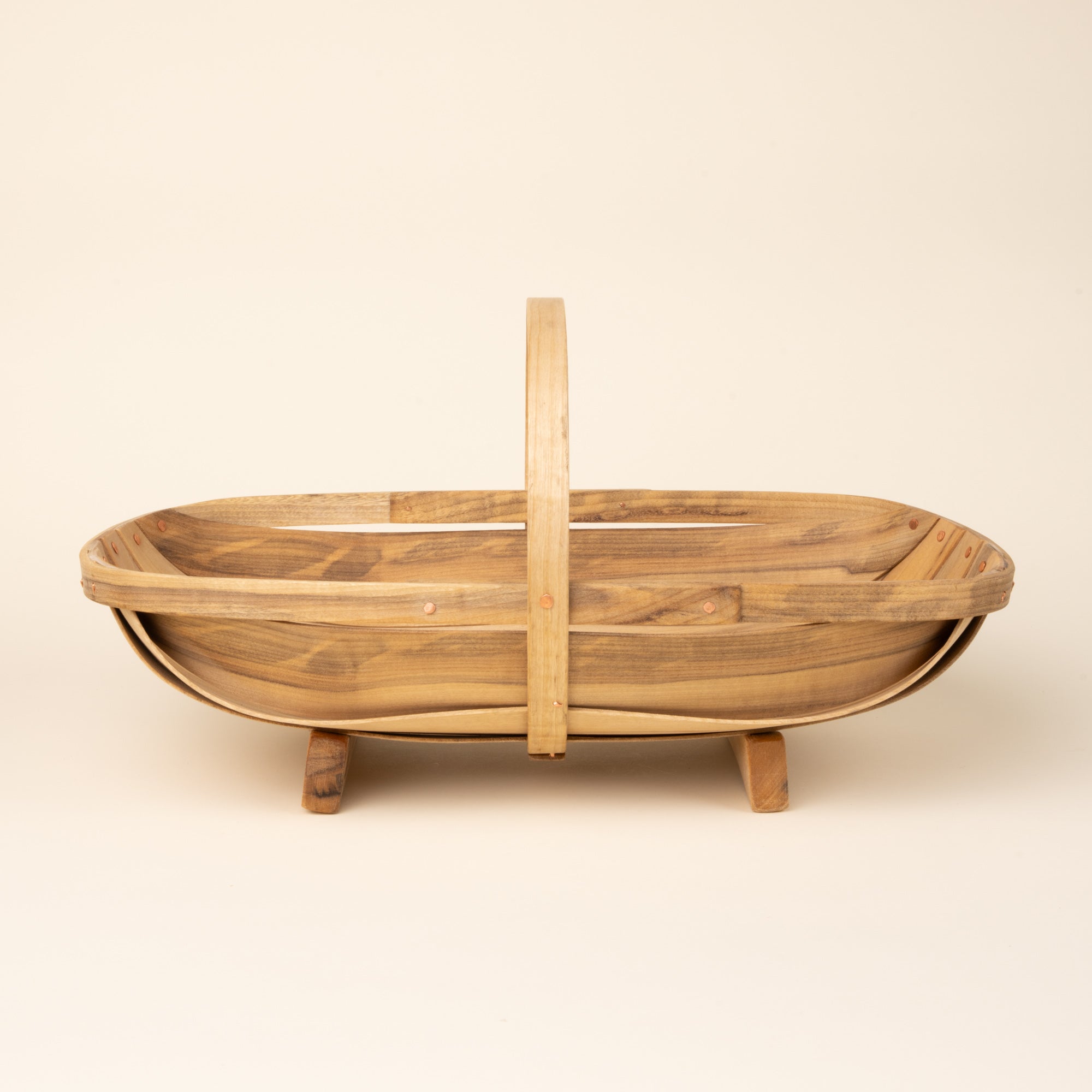 Large oval wooden gathering trug basket with a center handle and small feet.