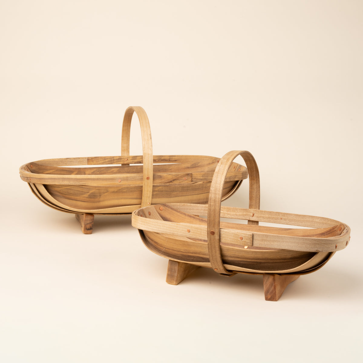 Small and large oval wooden gathering trug basket with a center handle and small feet.