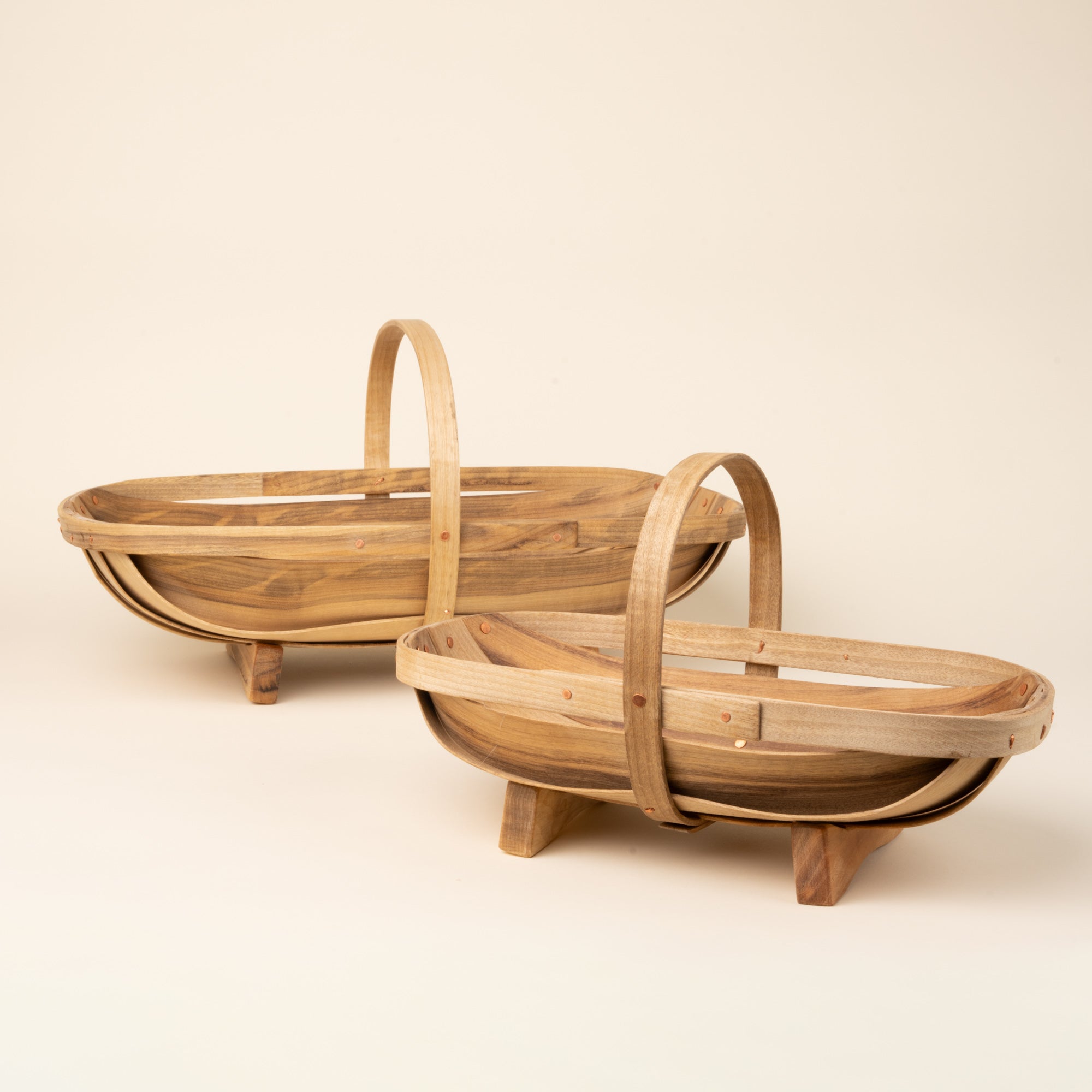 Small and large oval wooden gathering trug basket with a center handle and small feet.