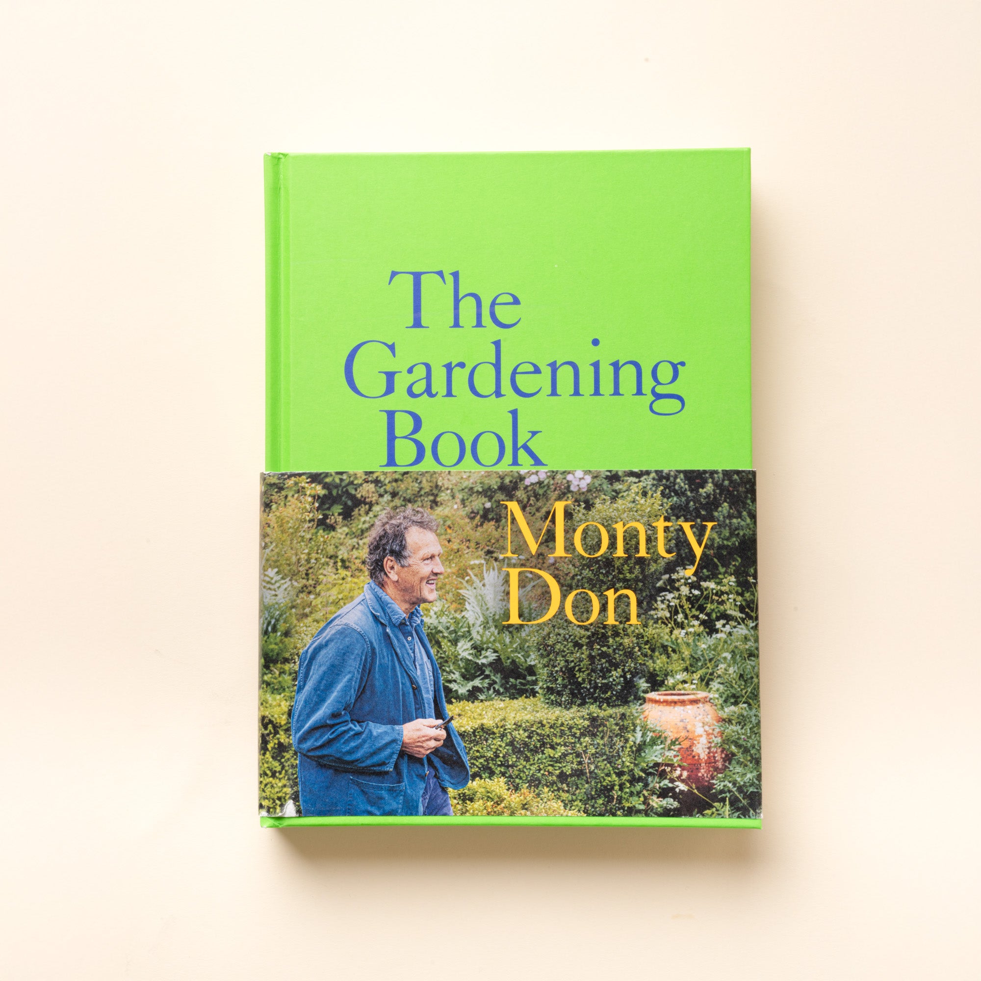 Green book cover titled “The Gardening Book” by Monty Don, featuring author in a lush garden scene.