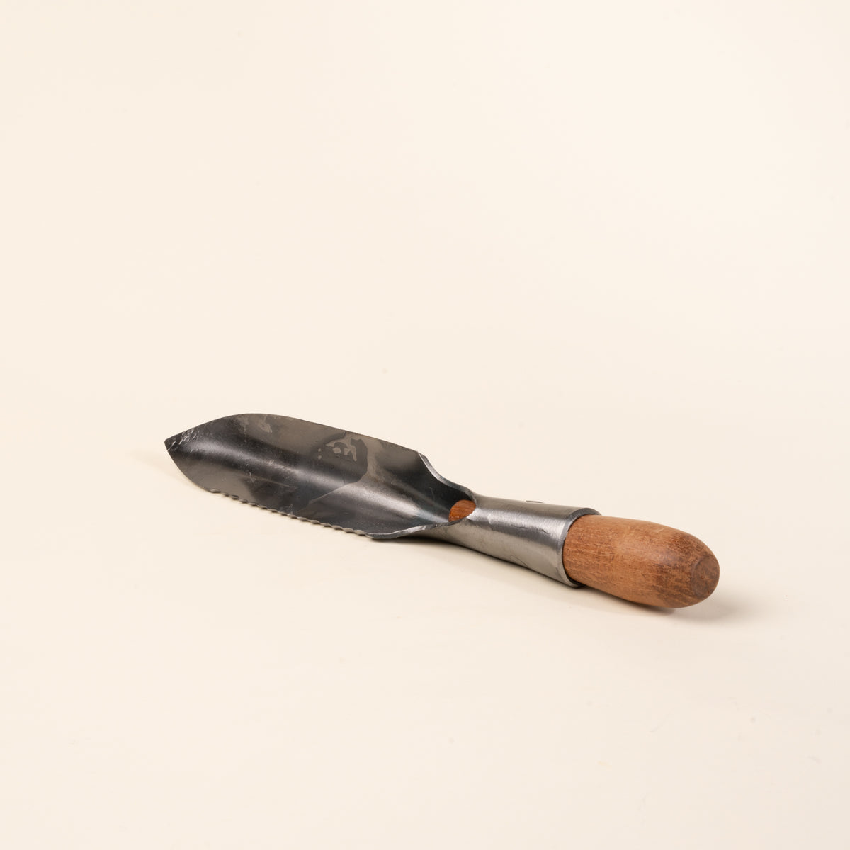 Handheld garden trowel with a serrated edge and wooden handle.