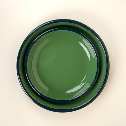 A nesting enamel side plate and dinner plate in green with a dark rim.