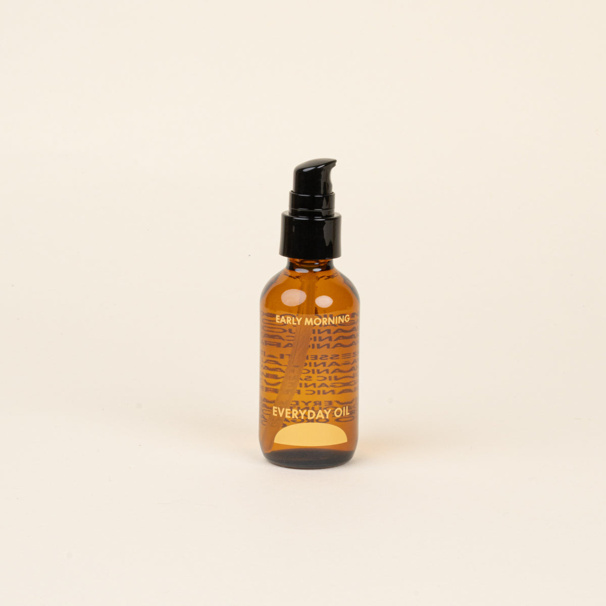 Amber glass bottle with black cap and label that reads 'Early Morning Everyday Oil' on a beige background.