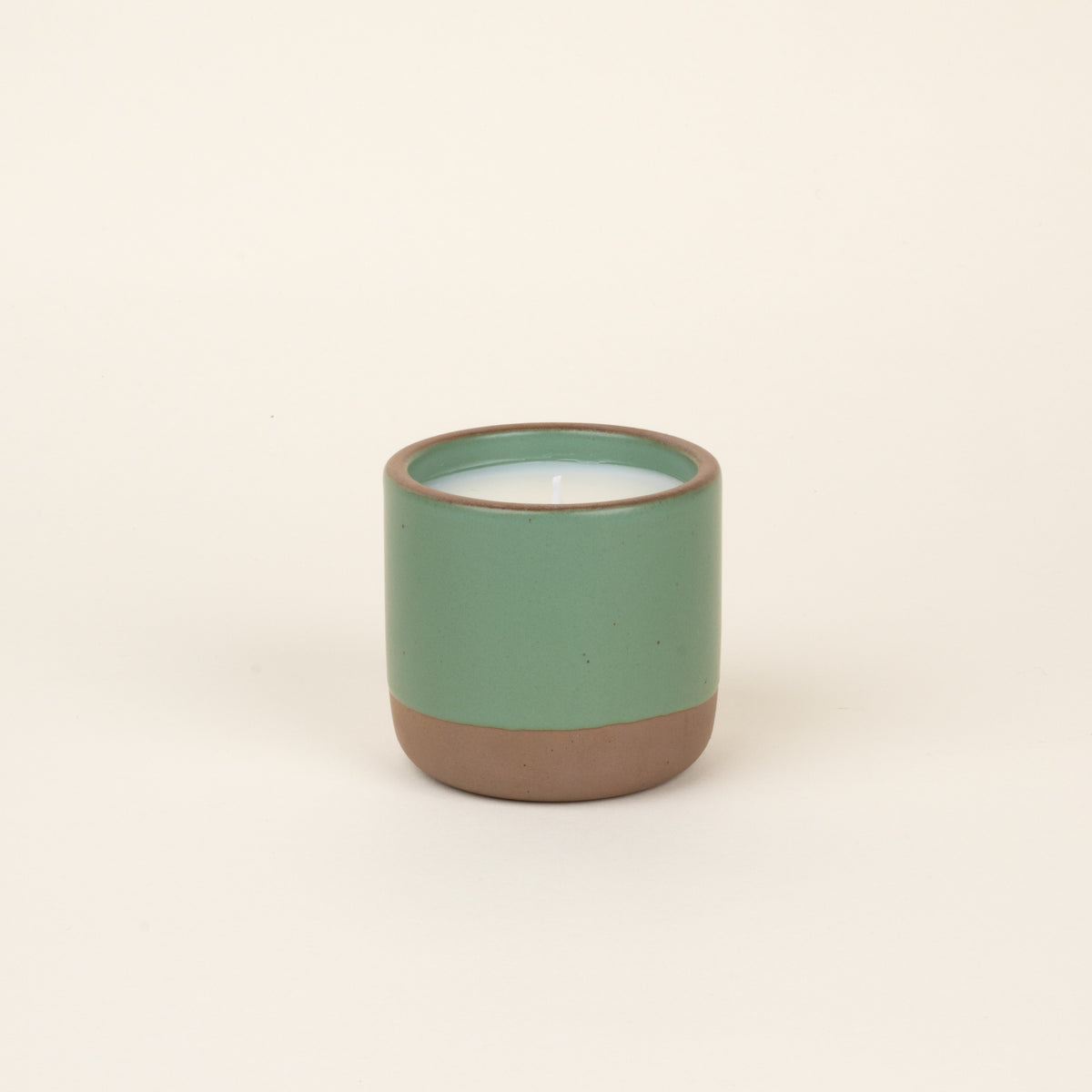 Green ceramic candle with a natural clay base, shown on a neutral background.