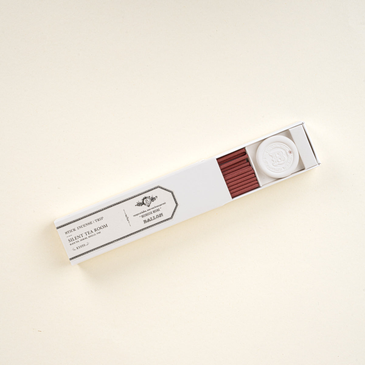 Open box of stick incense labeled “Silent Tea Room,” showing red incense sticks and a small holder on a neutral background.