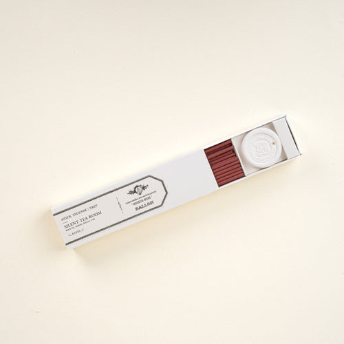 Open box of stick incense labeled “Silent Tea Room,” showing red incense sticks and a small holder on a neutral background.