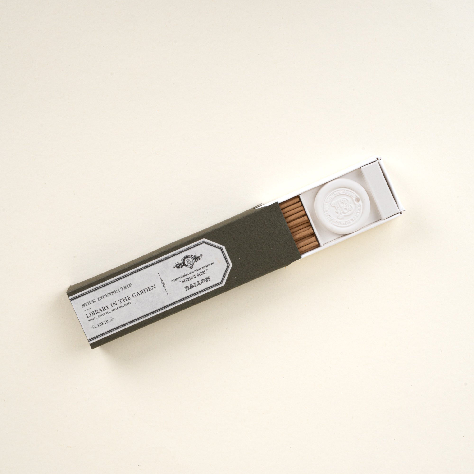 Open box of stick incense labeled “Library in the Garden,” showing incense sticks and a small holder on a neutral background.