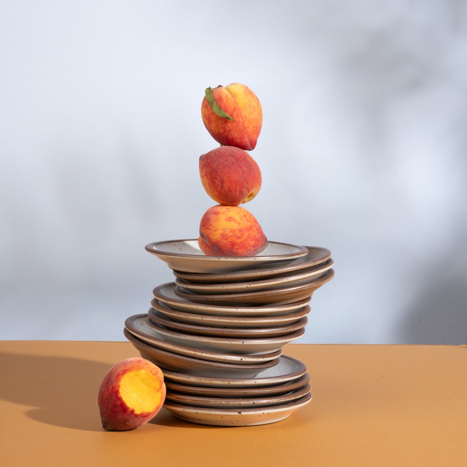 Plates artfully arranged on a stack with peaches.