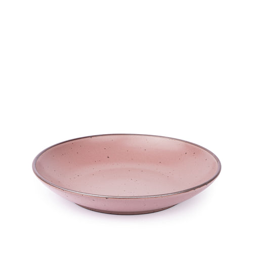A large ceramic plate with a curved bowl edge in a soft pink color featuring iron speckles and an unglazed rim.
